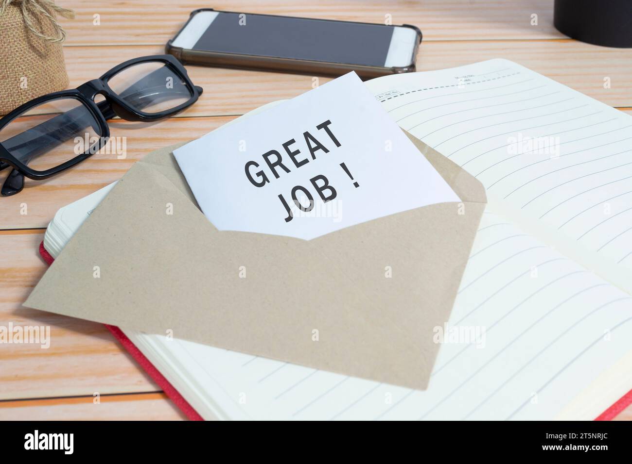 Card in brown envelope with words GREAT JOB on office desk. Positive