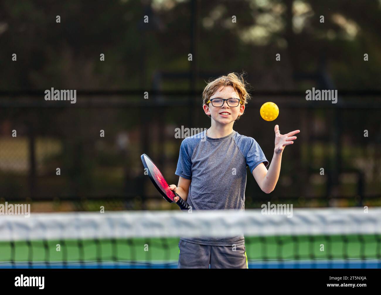 Young Boy playing pickleball on court Stock Photo