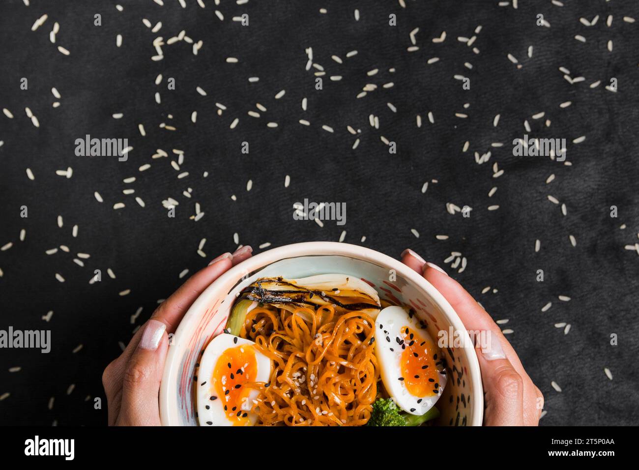 Close up woman s hand holding bowl noodles with boiled eggs rice grains