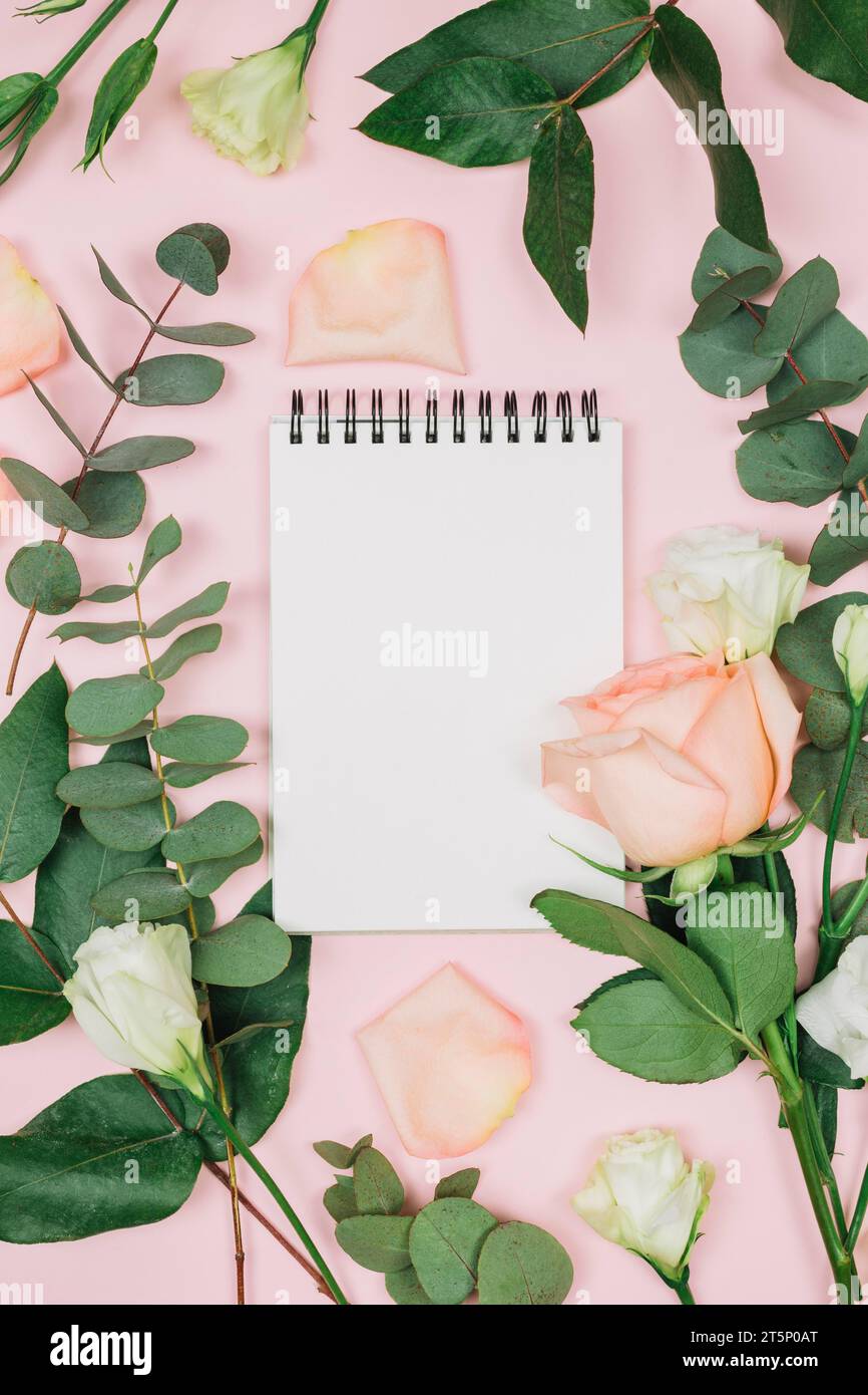 Blank spiral notepad with rose eustoma flowers against pink background ...