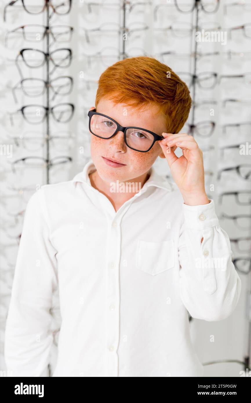 Innocent boy with black frame spectacle standing optics store Stock Photo
