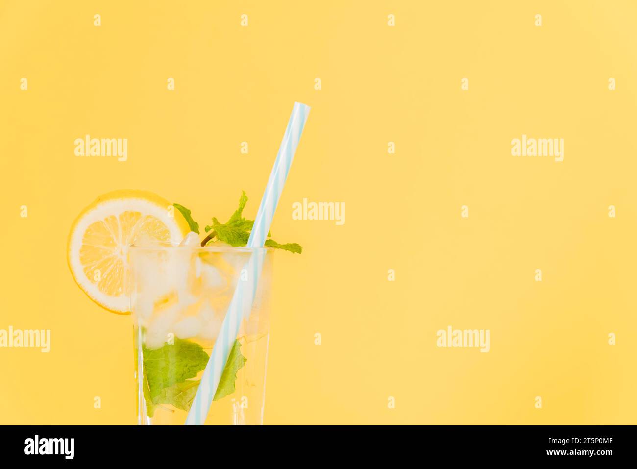 Lemon cocktail with plastic straw yellow background Stock Photo