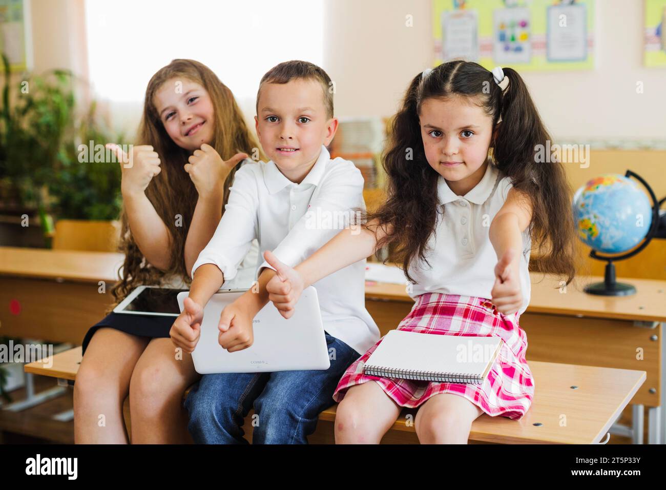 Children sitting school desk gesturing Stock Photo - Alamy