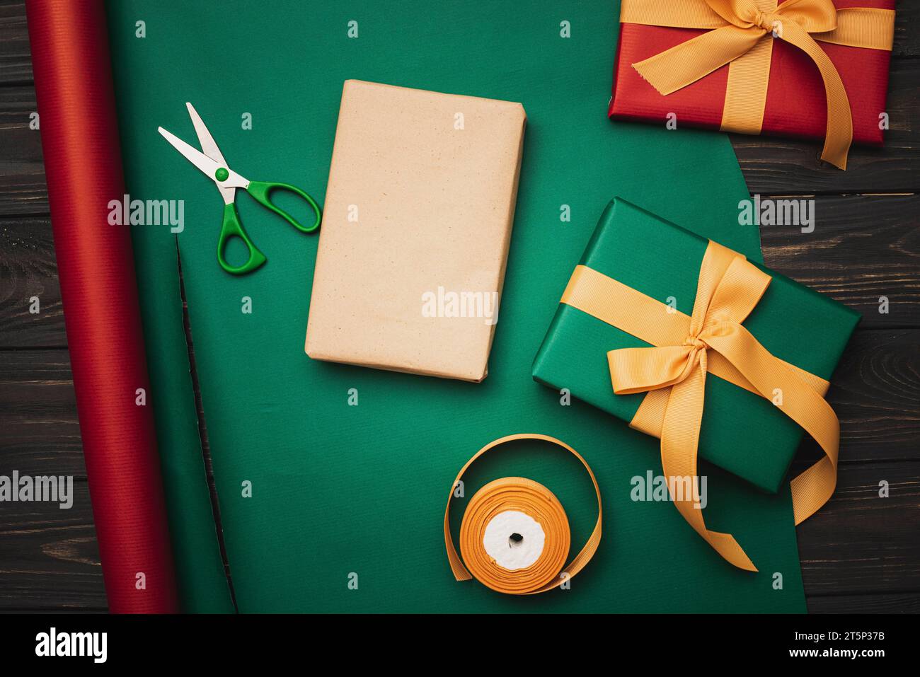 top view of green wrapping paper, scissors and present with red