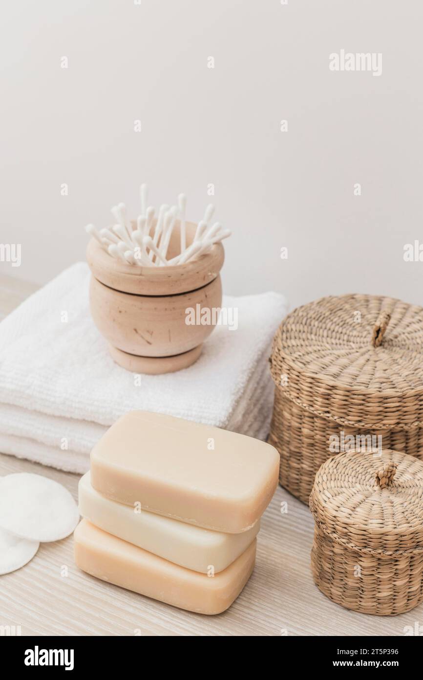 Close up soaps sponge cotton swab towel wicker basket wooden surface Stock Photo