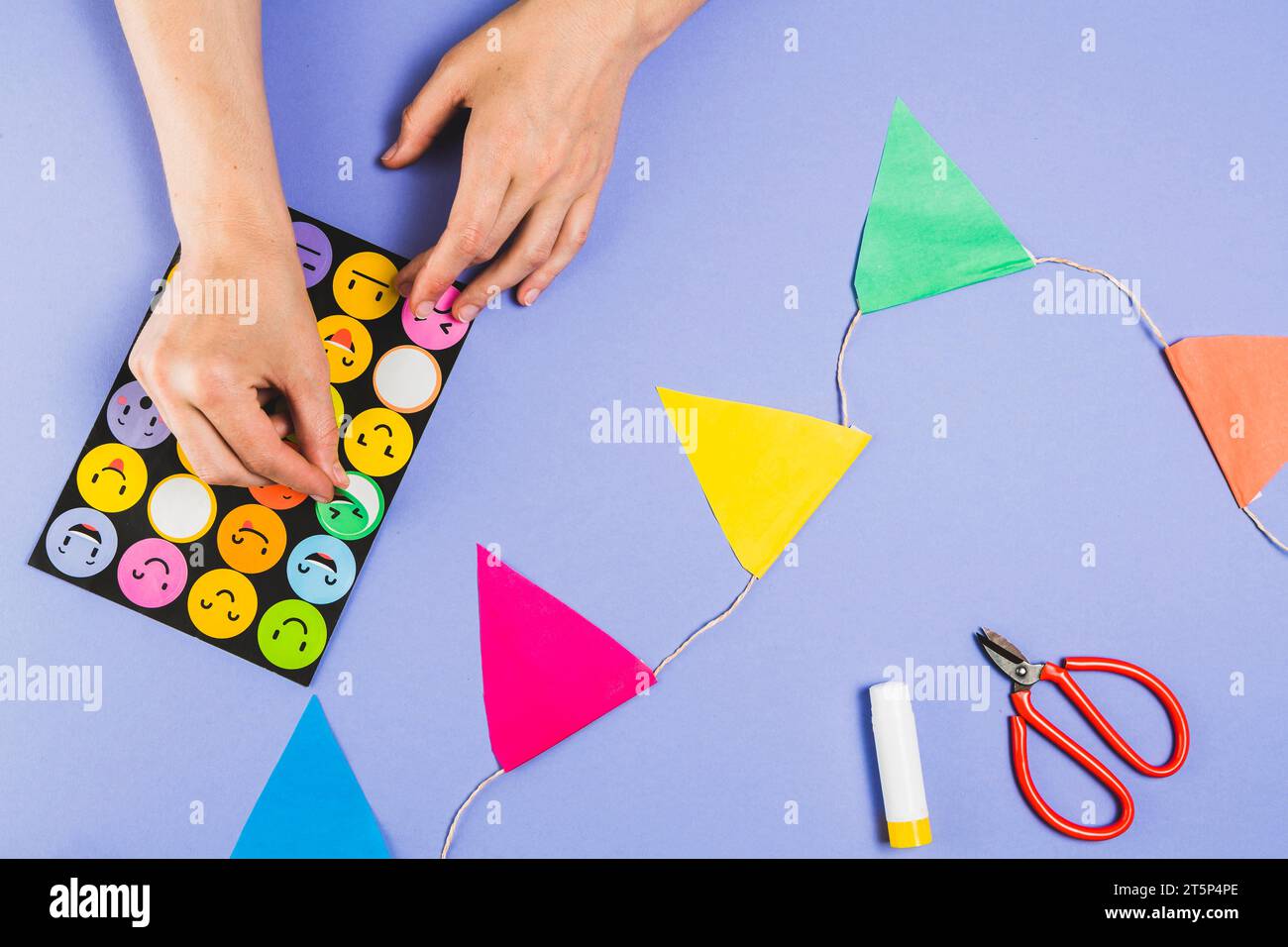 Human hand removing emoji from stickers set making craft purple surface