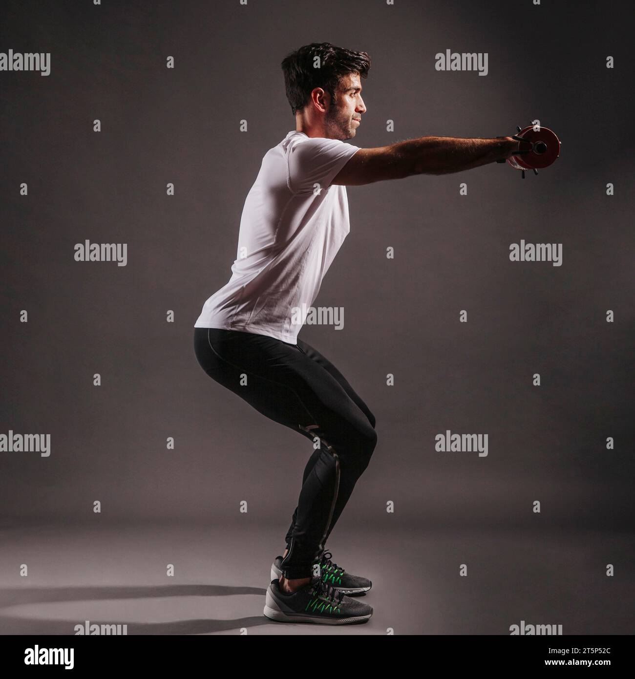 Man squatting with dumbbells Stock Photo