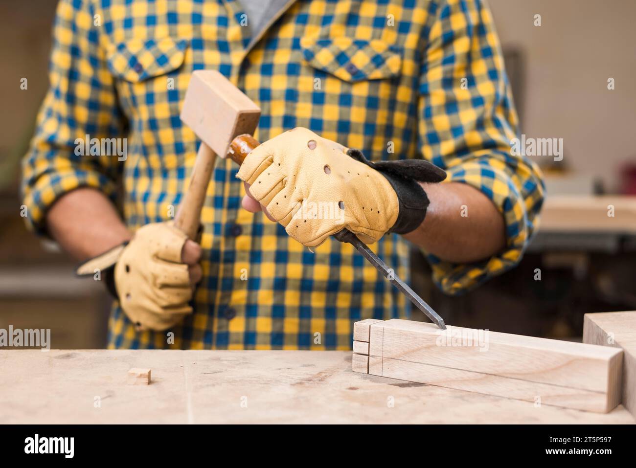 Mid section male carpenter hitting chisel with hammer rectangular block Stock Photo