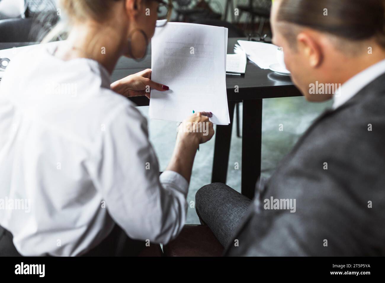 Rear view two businesspeople examining document caf Stock Photo