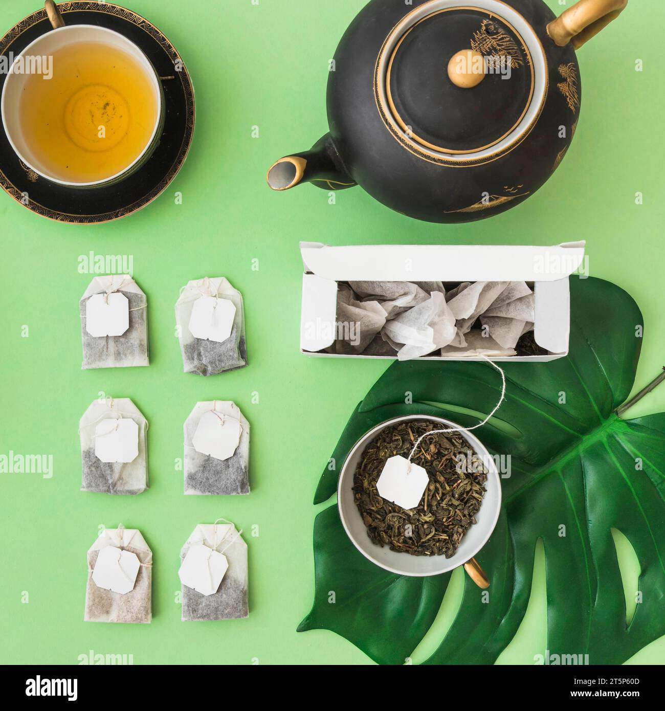 Row different tea bags with tea cup teapot pale green backdrop Stock