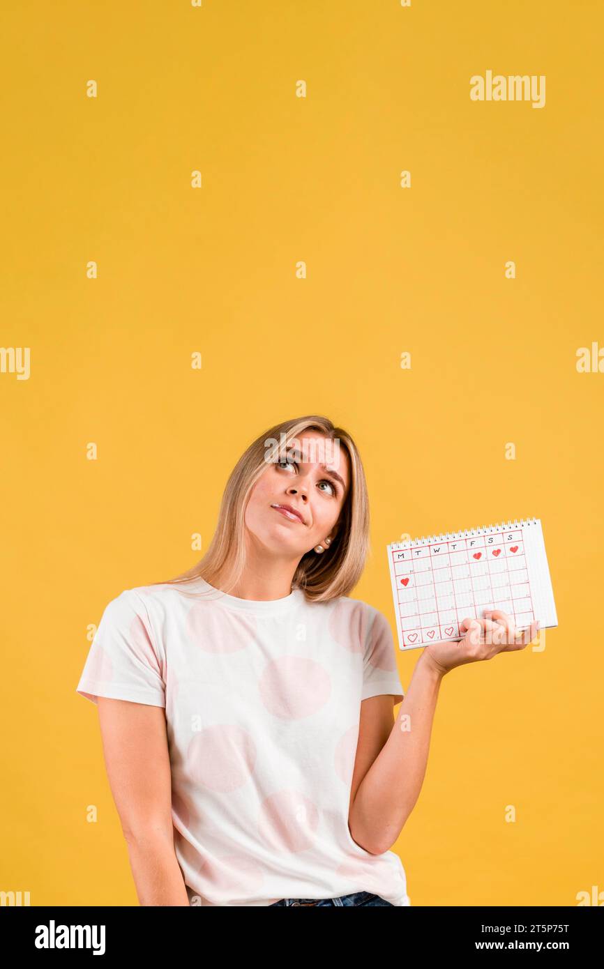 Woman looking up holding menstruation calendar Stock Photo