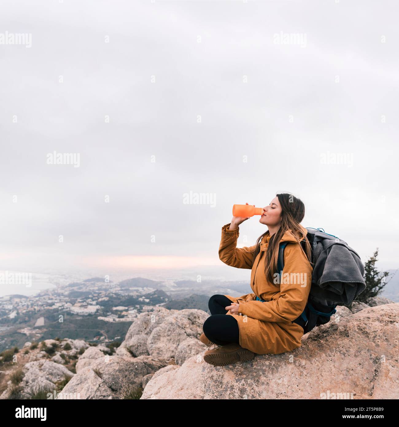 Female backpacker sitting top mountain drinking water Stock Photo