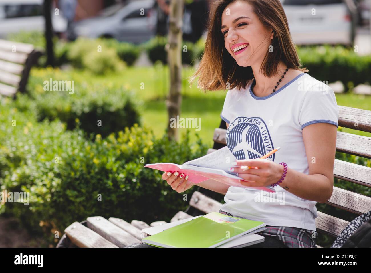 Girl sitting bench holding notebook smiling Stock Photo