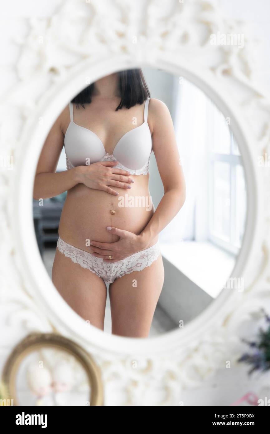 Pregnant woman checking herself mirror Stock Photo