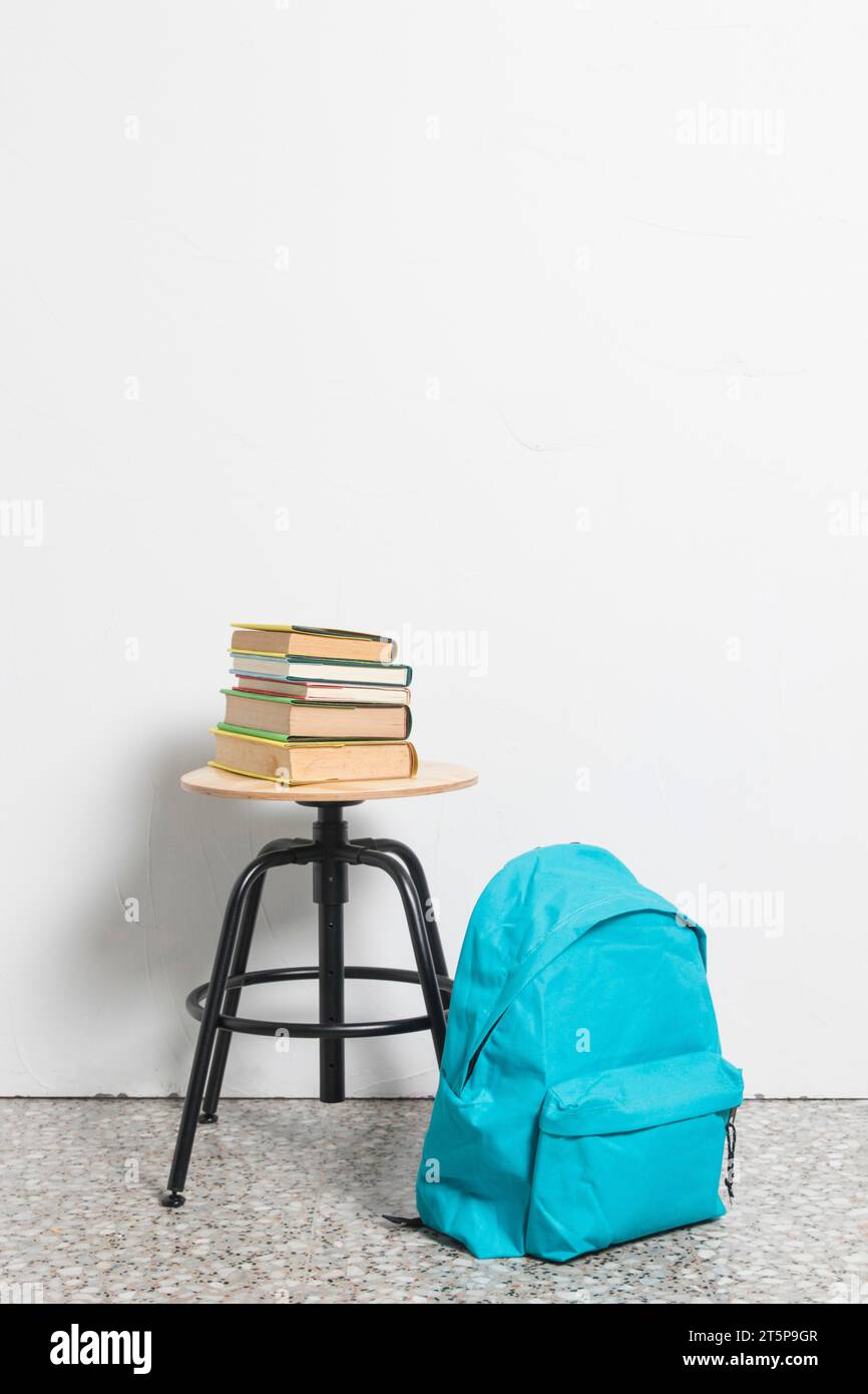 Stack books stool chair with blue schoolbag floor Stock Photo