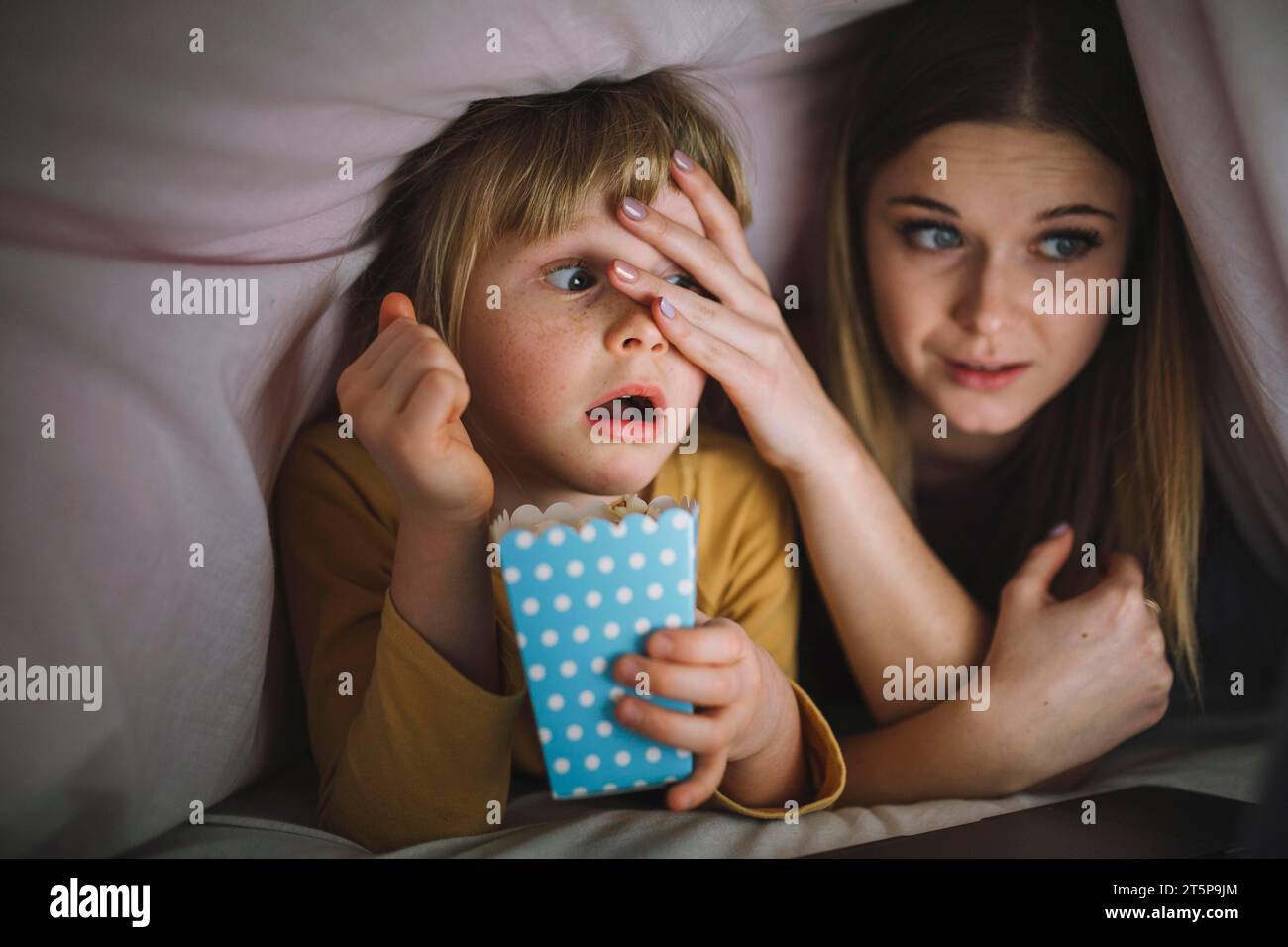 Sisters watching scary film blanket Stock Photo