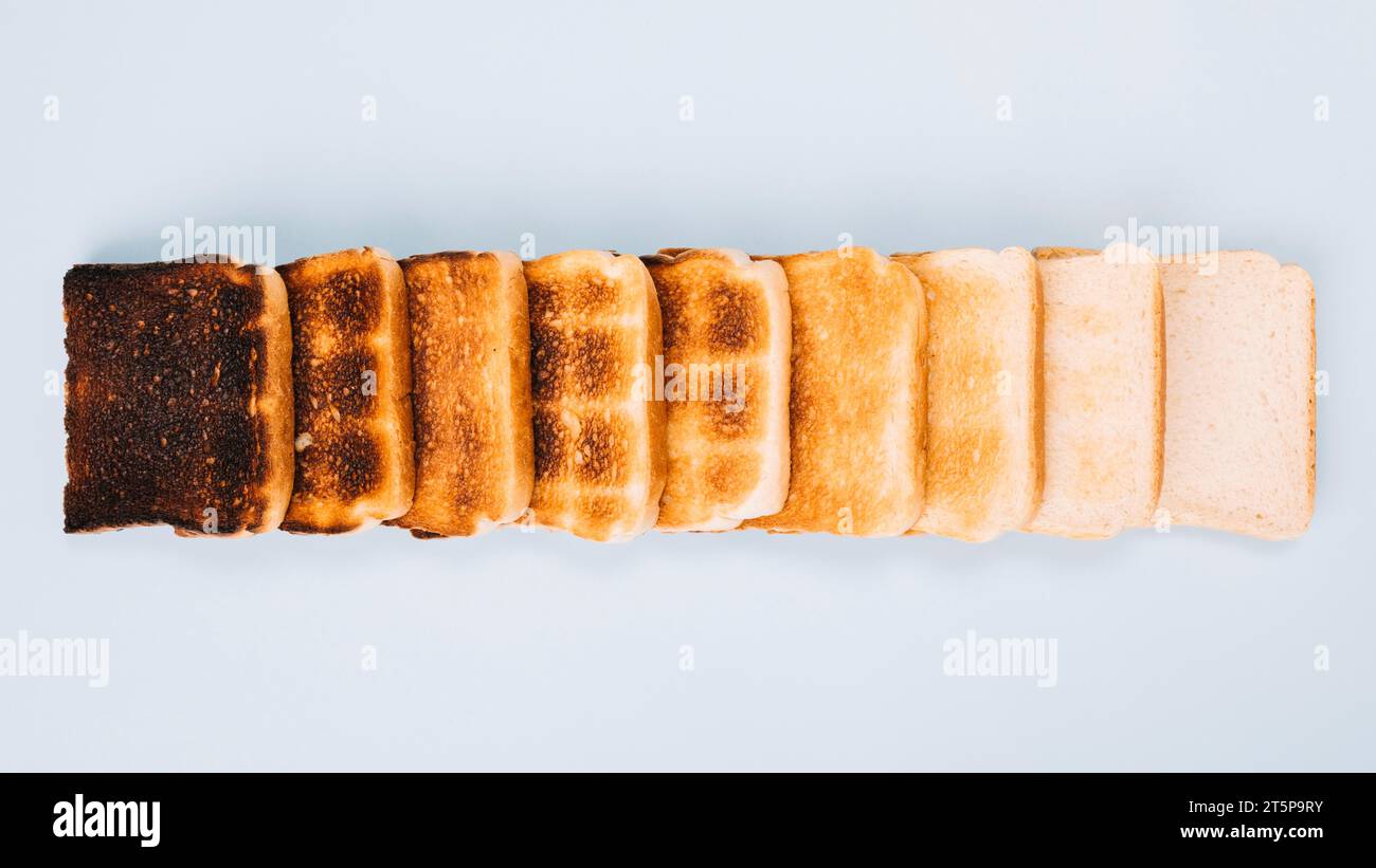 Top view bread slices varying stages toasting arranged row white background Stock Photo