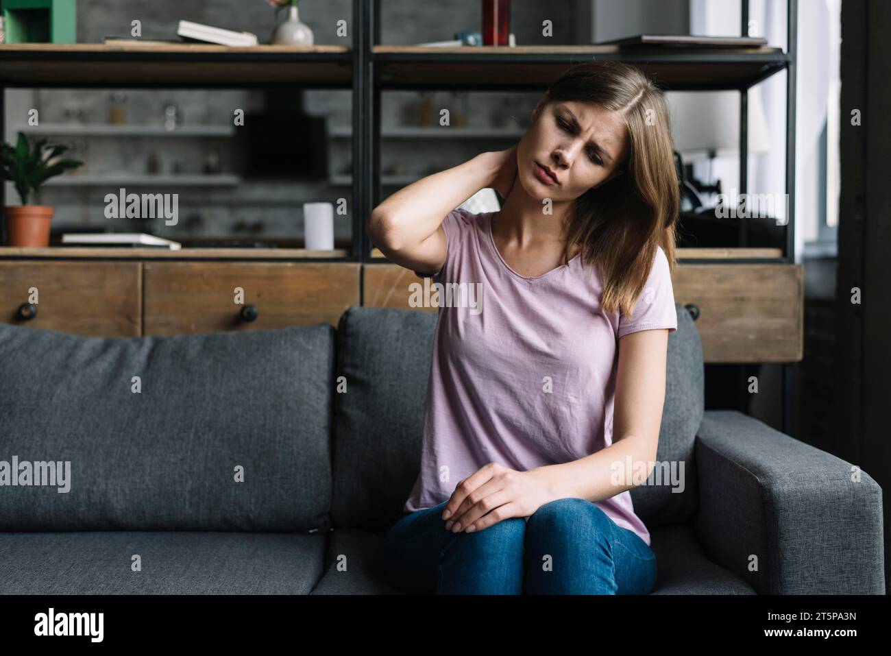 Woman sitting sofa suffering from neck pain Stock Photo Alamy