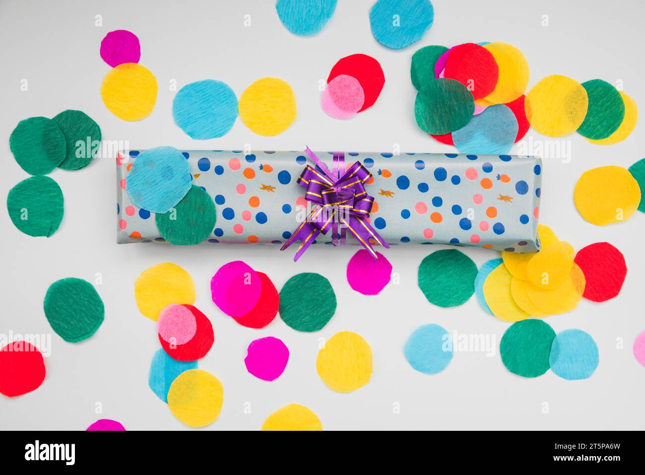 Wrapped polka dot gift box with circular cut out colored paper white background Stock Photo