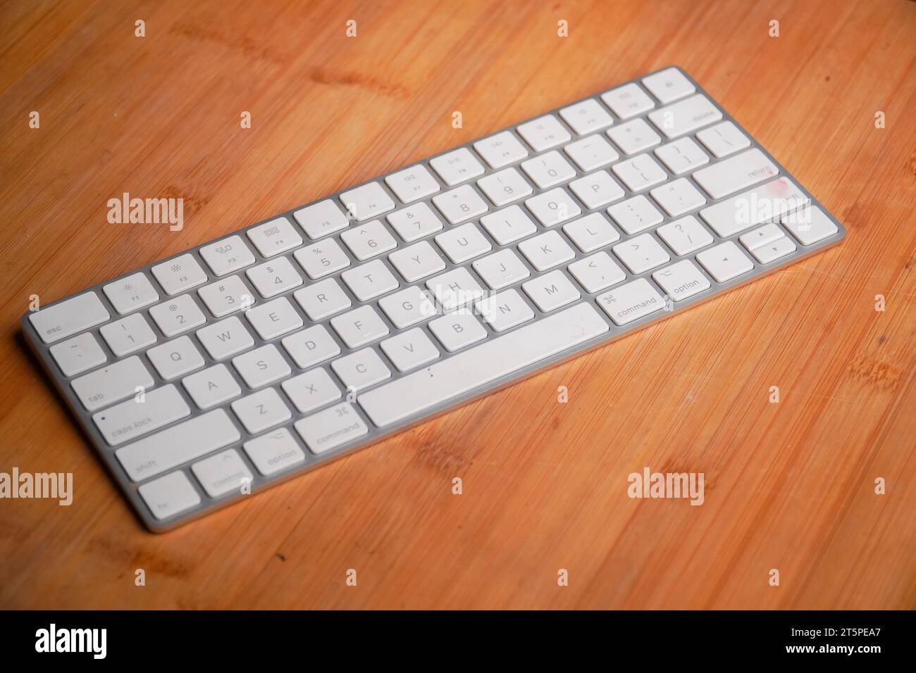 Small compact white computer keyboard on a bambo table. Minimalistic clean design Stock Photo