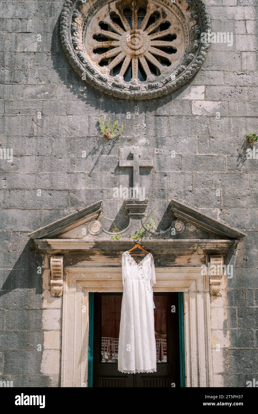 White wedding dress hangs on a hanger above the entrance to an ancient ...