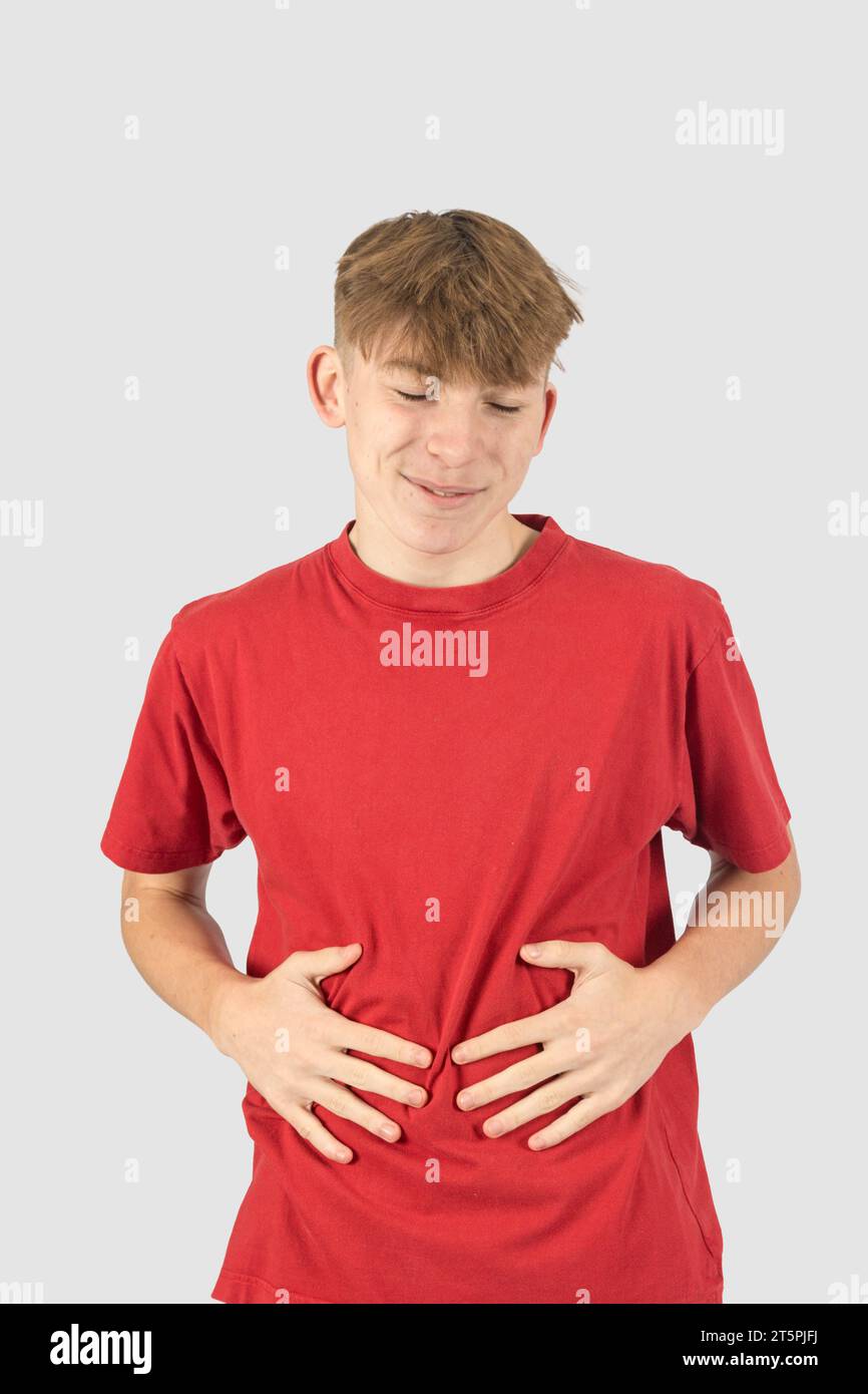 A studio portrait of a pleased fifteen year old teenage boy rubbing his ...