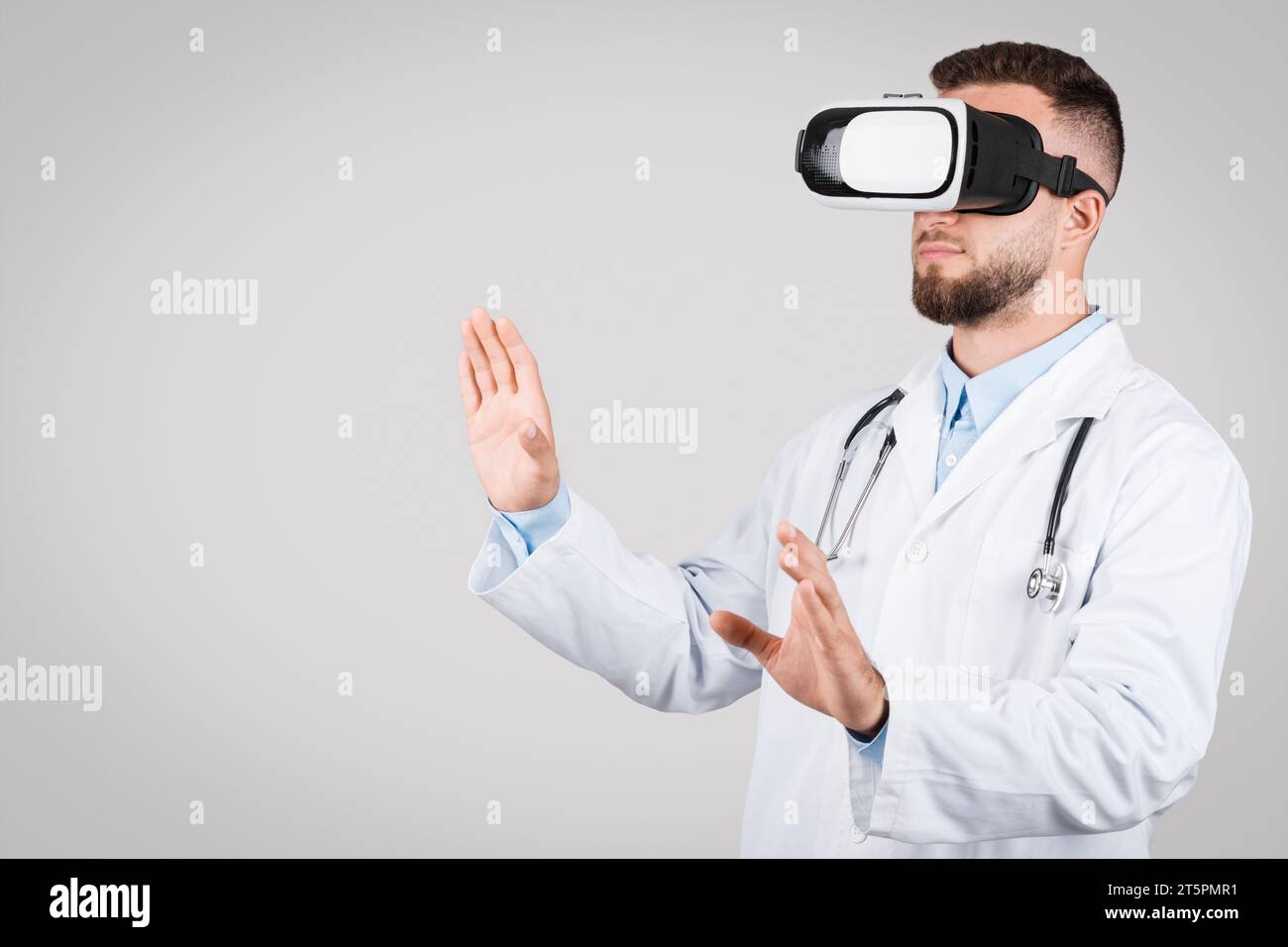 Doctor man using virtual reality headset, interacting on grey background, free space Stock Photo