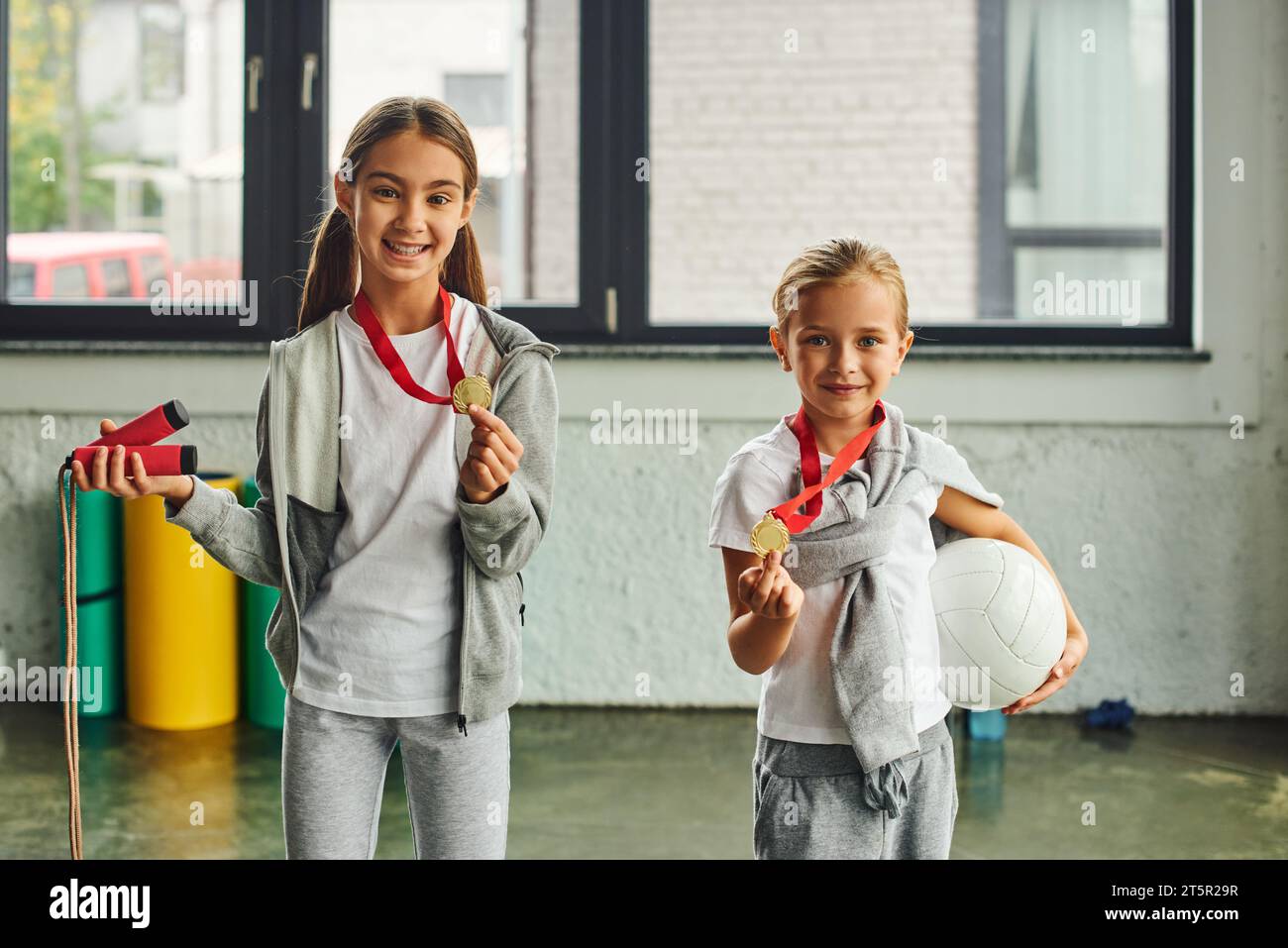 cute preadolescent girls posing with golden medals with jump rope and