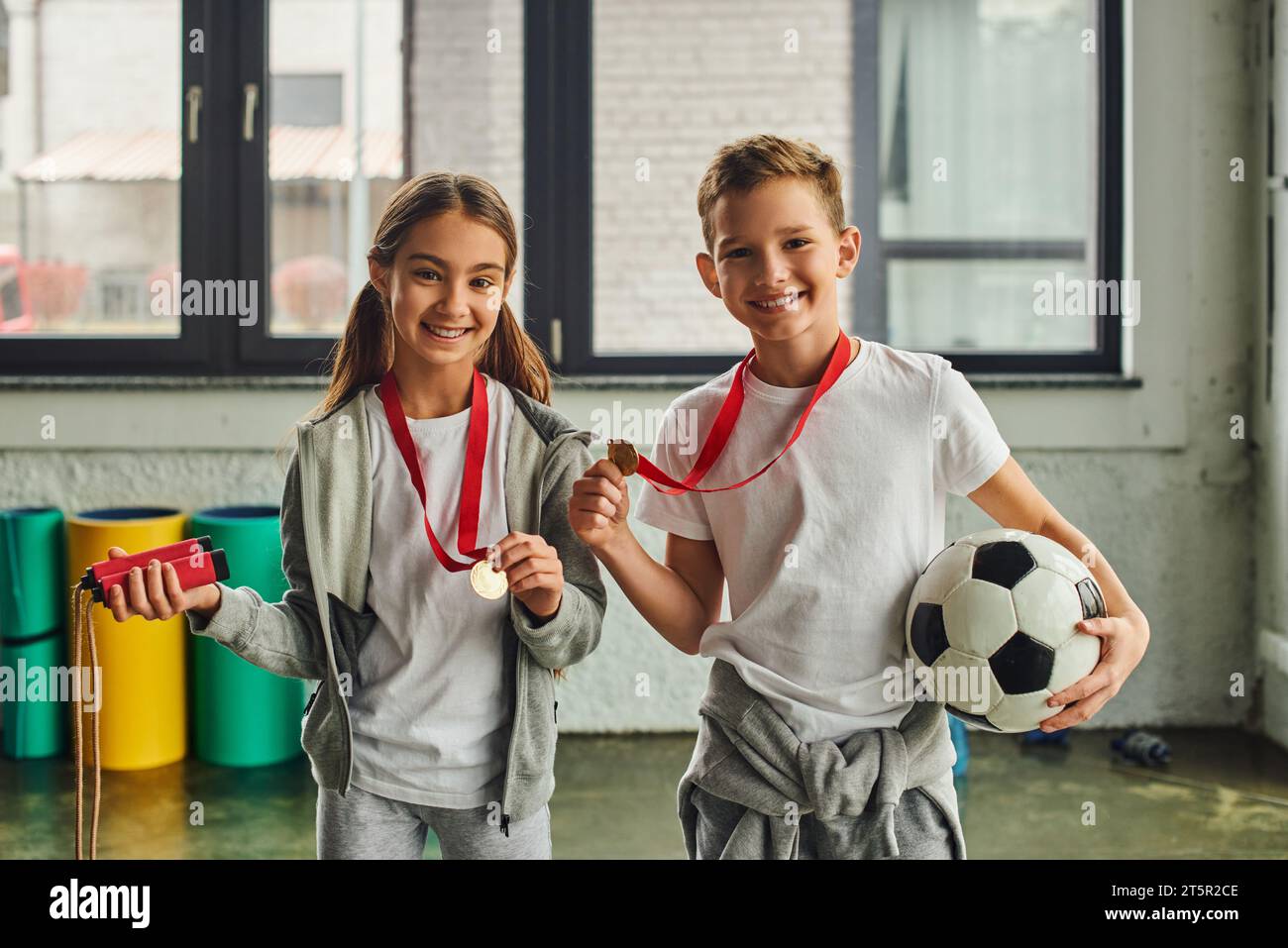 little girl with medal holding jump rope and cute boy posing with