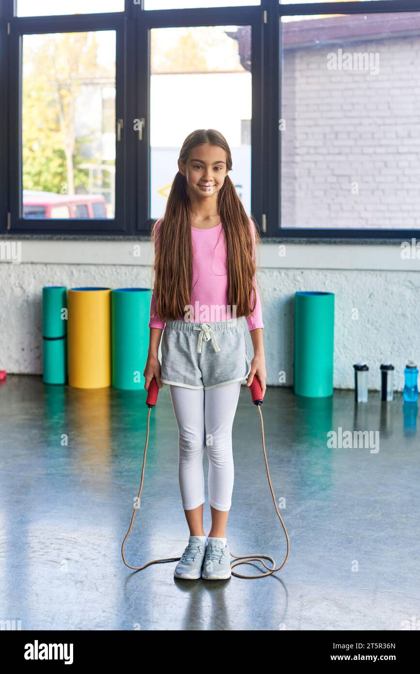 vertical shot of pretty little girl with long hair posing with jump ...
