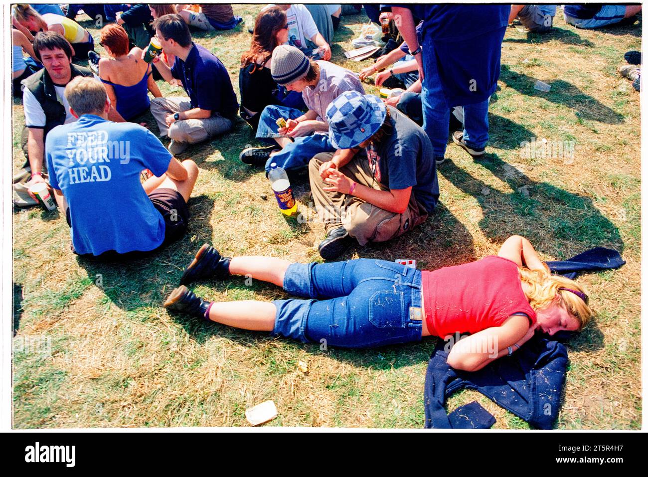 BRITPOP and ROCK FANS, READING FESTIVAL, 1998: The extreme heat and the long days are too much for this woman and she crashes out to sleep while her friends roll cigarettes. A scene from the site and crowd in the Main Stage arena area at Reading Festival 1998 on 28-30 August 1998 in Reading, England UK. Photo: Rob Watkins Stock Photo
