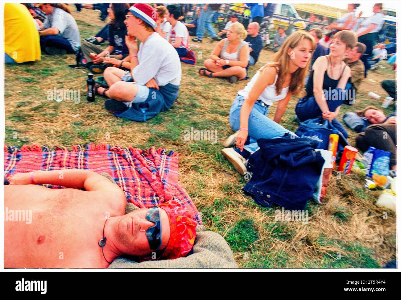 BRITPOP and ROCK FANS, READING FESTIVAL, 1998: A man sunbathes and seems to be getting burned by the main stage. A scene from the site and crowd in the Main Stage arena area at Reading Festival 1998 on 28-30 August 1998 in Reading, England UK. Photo: Rob Watkins Stock Photo