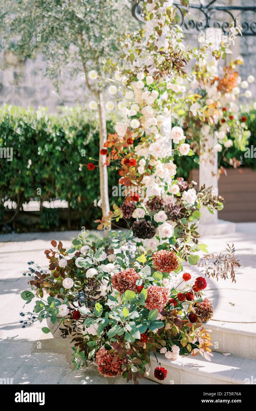 Column of a wedding arch in the garden entwined with colorful flowers Stock Photo
