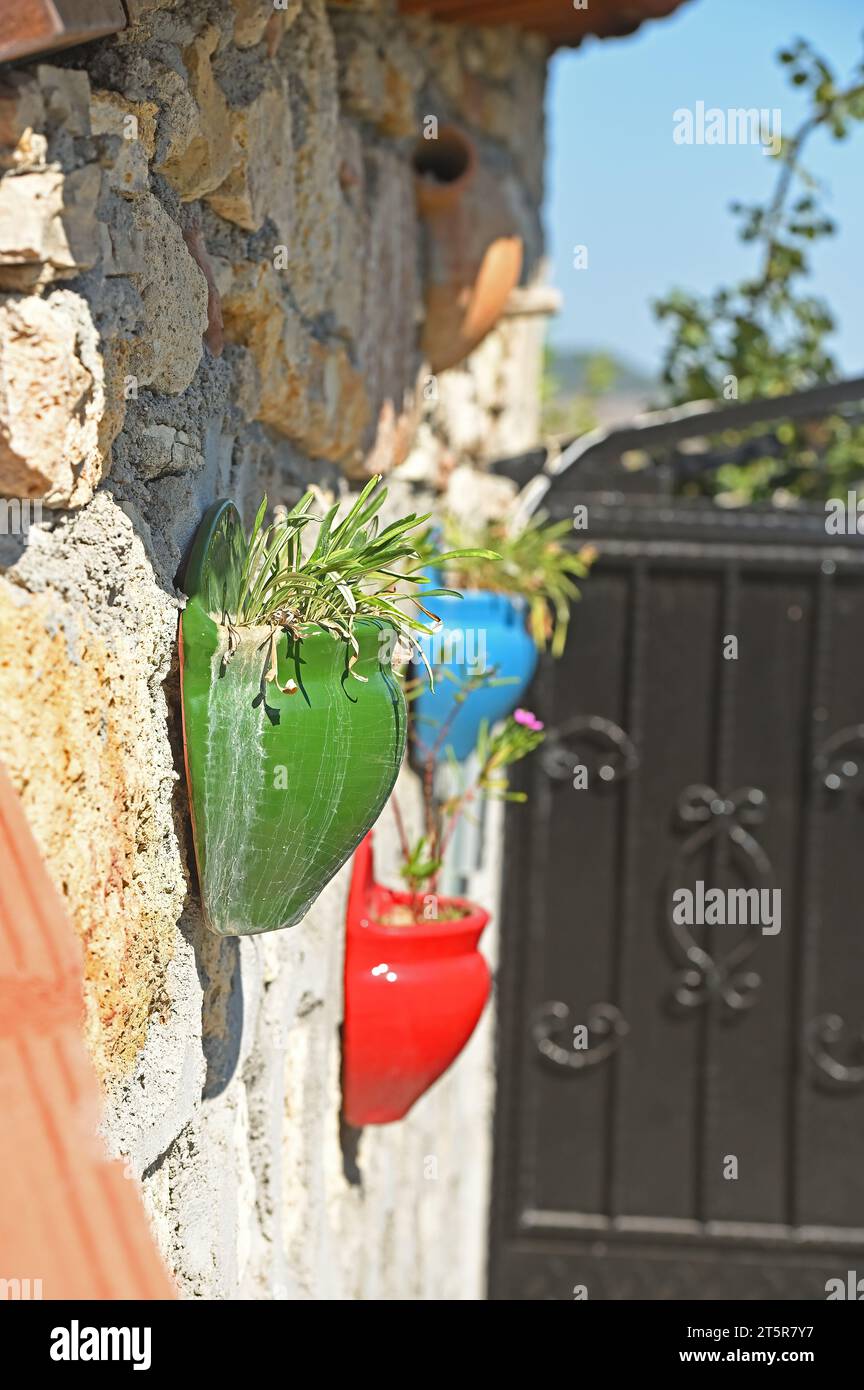 Decorative flower pots on the stone wall. Red, green and blue pots. Stock Photo