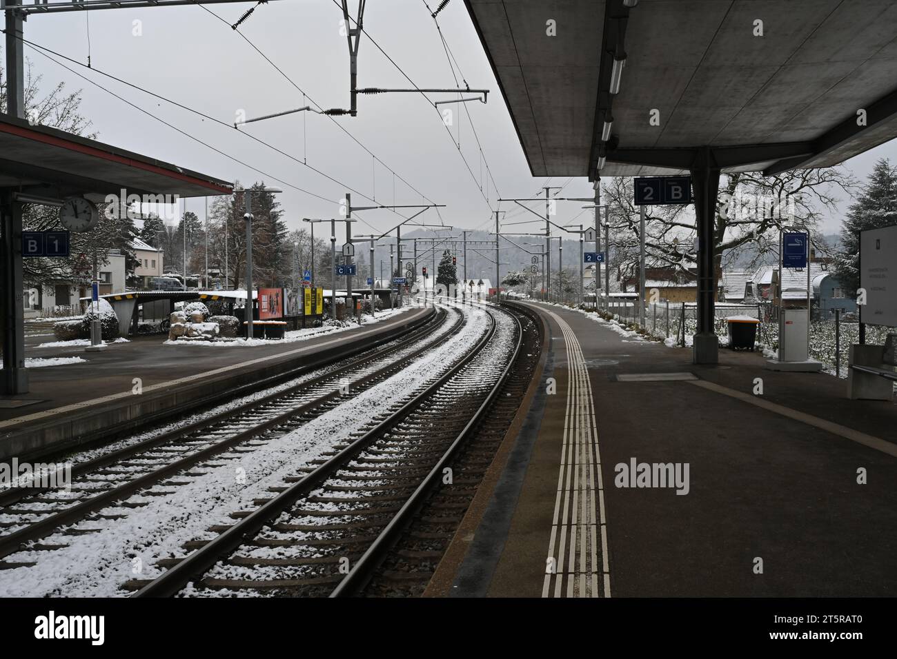 Railway platform and rails of a small village station in winter. There is snow on the railway tracks. Stock Photo