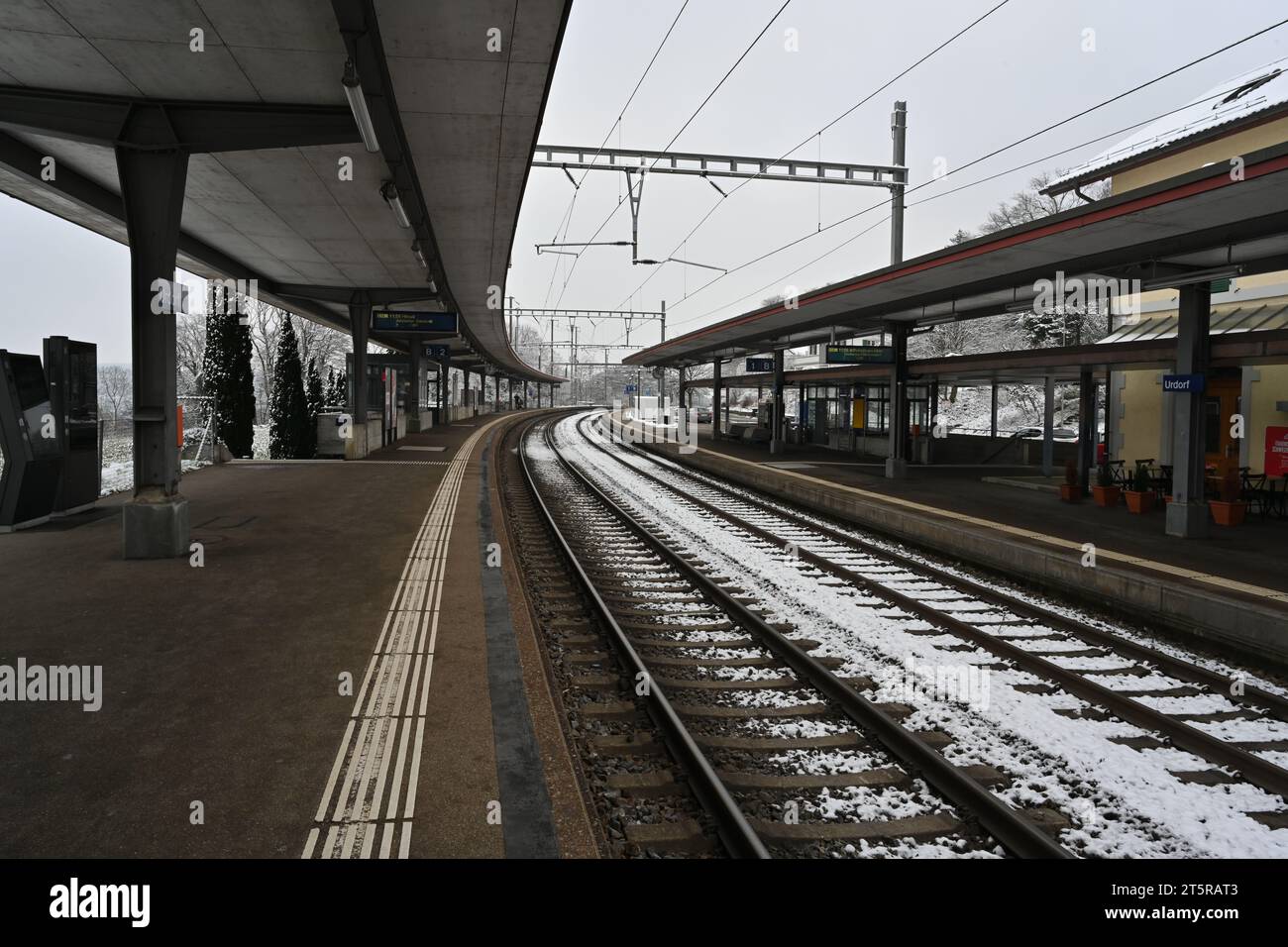 Railway platform of a small village station in winter. There is snow on the railway tracks. Stock Photo