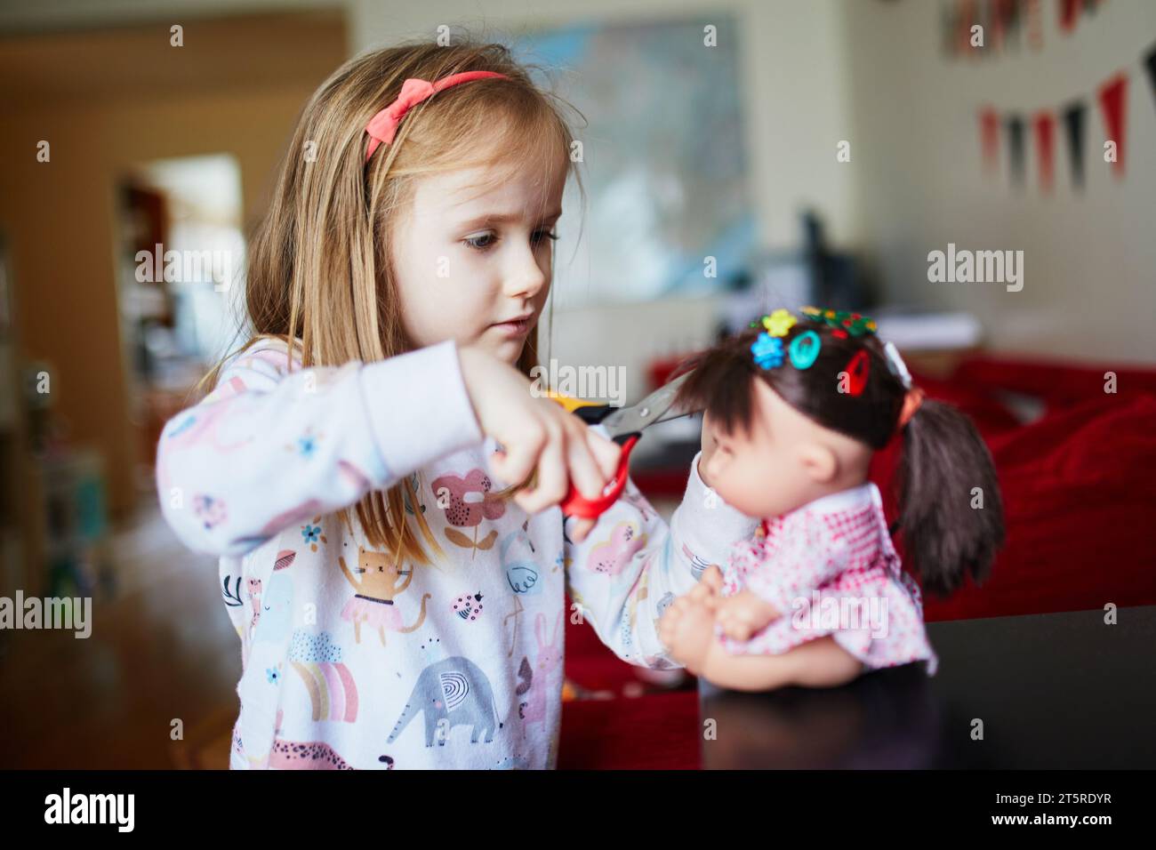 Adorable preschooler girl playing house at home. Child making haircut
