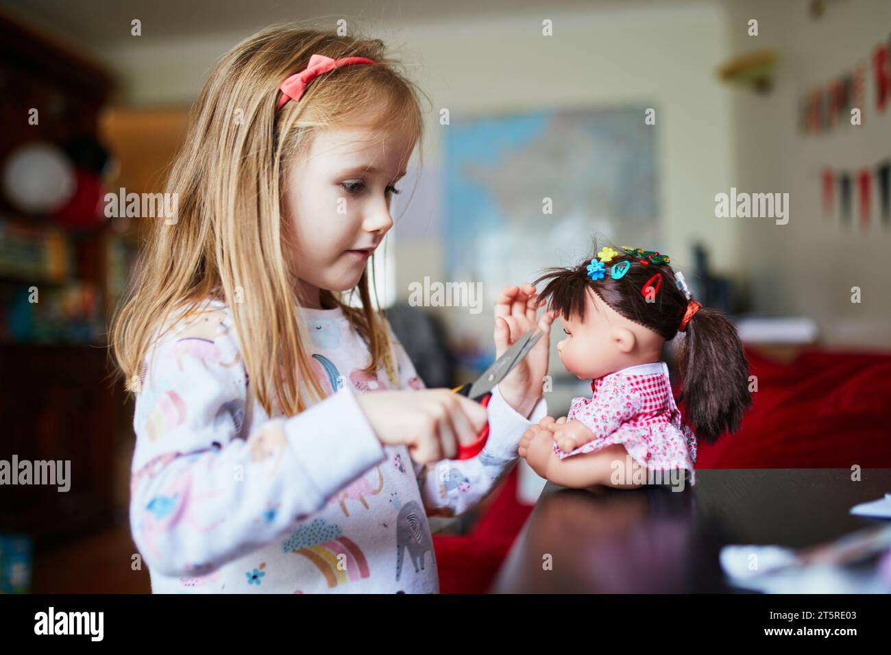 Adorable preschooler girl playing house at home. Child making haircut