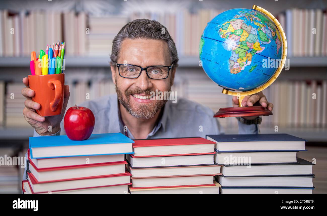 Man geographer with books in classroom. Knowledge and education concept. school teacher with book in classroom. teacher in classroom. Teachers Day. Tu Stock Photo