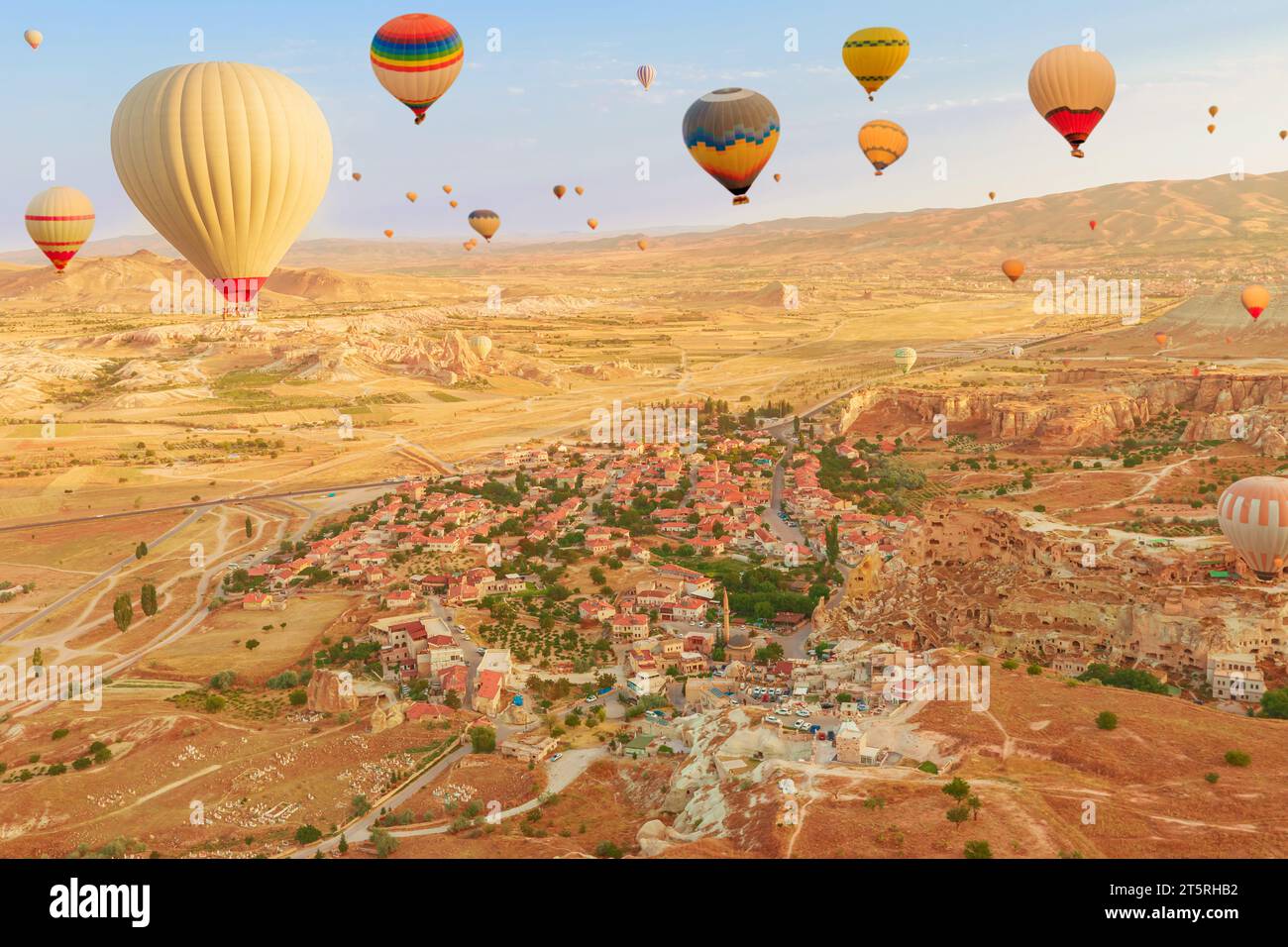 Balloons into Cappadocia's vast skyline. The brilliant hues of balloons capture dwindling daylight, casting a mesmerizing illumination on the surreal Stock Photo