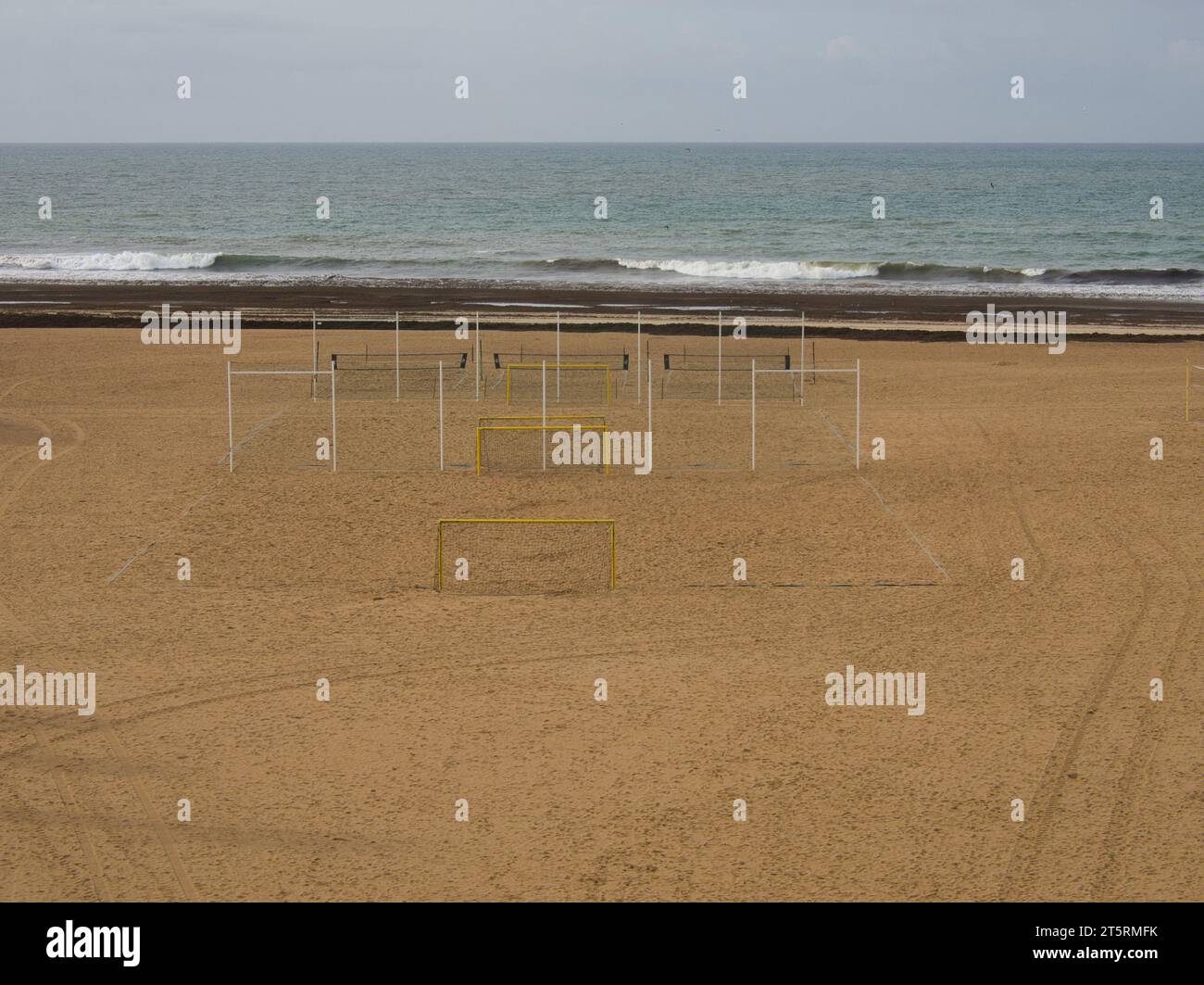 Deserted football and beach volleyball playing fields in the middle of the sandy beach with the sea in the background. Stock Photo