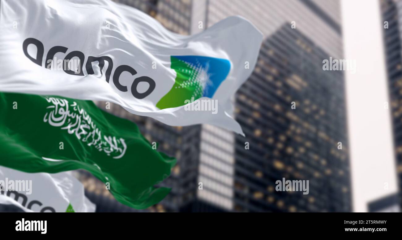 Dhahran, SA, Oct 20 2023: Flags of Aramco and Saudi Arabia waving in a financial district. Aramco is the Saudi national hydrocarbon company. Illustrat Stock Photo