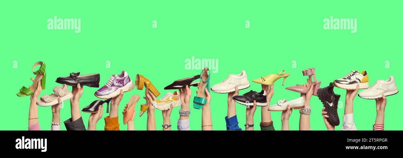 Many man's and woman's hands holding different color and style shoes on isolated green background with copy space. Banner for a website or fashion blo Stock Photo
