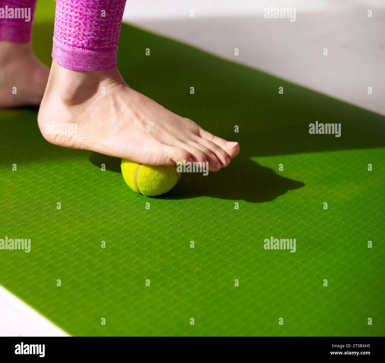 A tennis ball under female foot. Massage for relieve muscle tension
