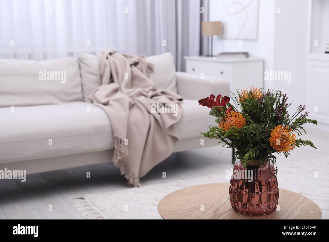 Vase with bouquet of beautiful leucospermum flowers on wooden table in living room Stock Photo