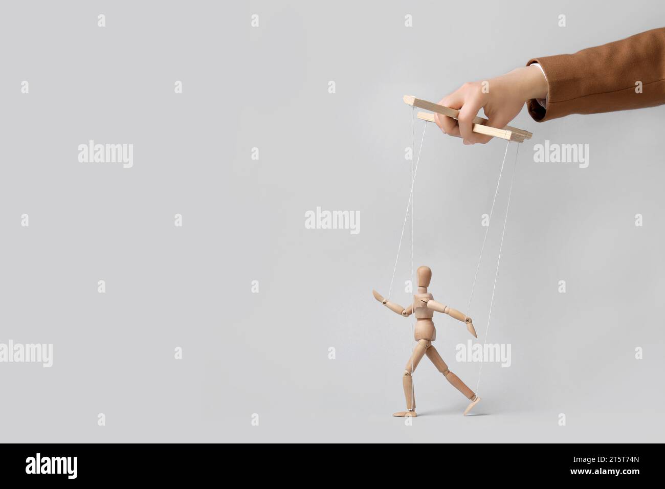Woman pulling strings of puppet on light grey background, closeup ...