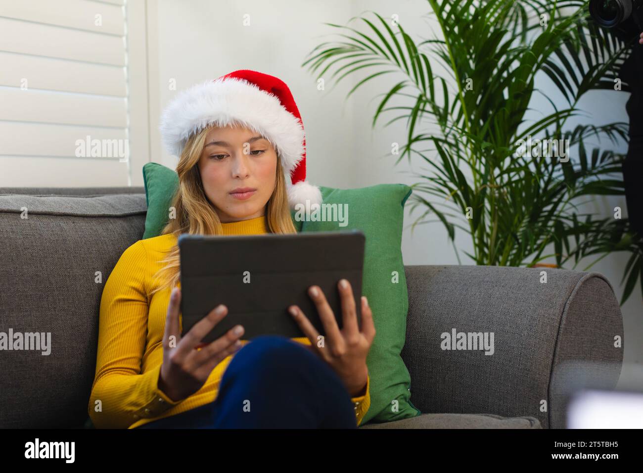 Happy caucasian woman in santa hat using tablet at christmas at home Stock Photo