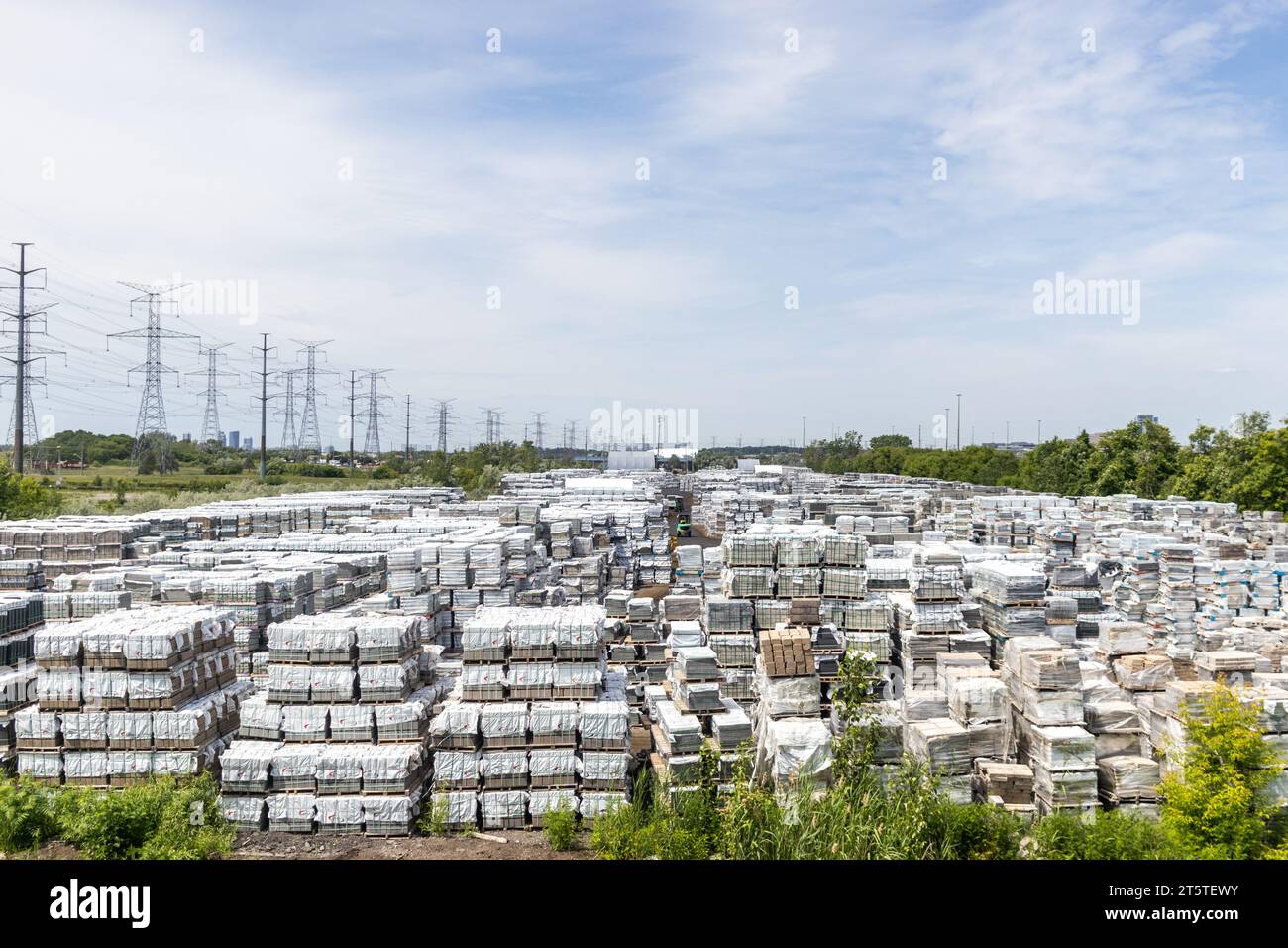 Industrial storage yard stacked materials power lines trees Stock