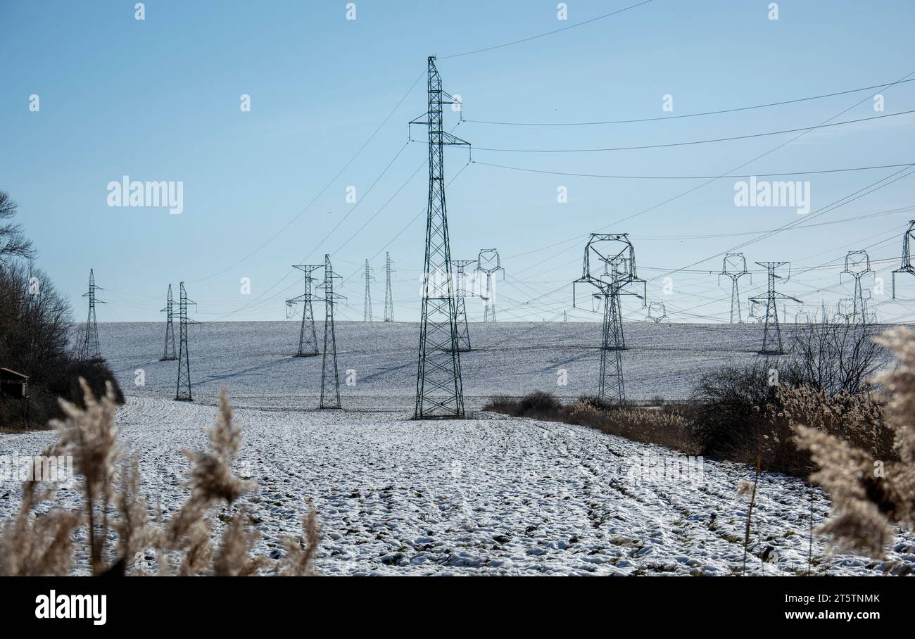 High voltage power towers in winter. Electricity pylons, transmission towers. Blue sky in the background. Stock Photo