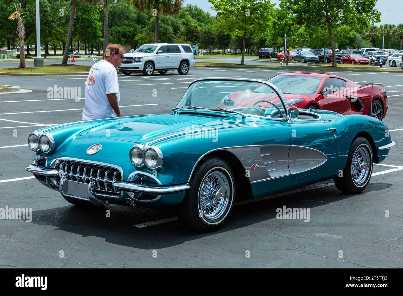 A man inspects an antique blue Chevrolet Corvette convertible sports